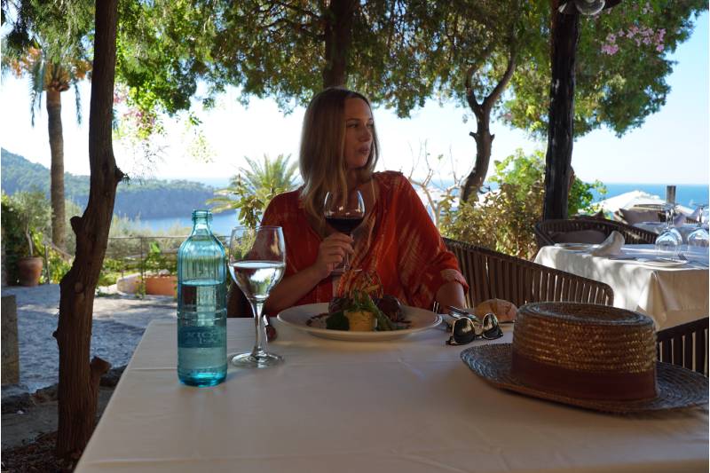 Mujer comiendo en el restaurante con el mar de fondo