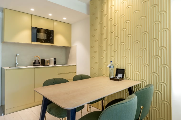 Modern kitchen area in green tones, open to the living room