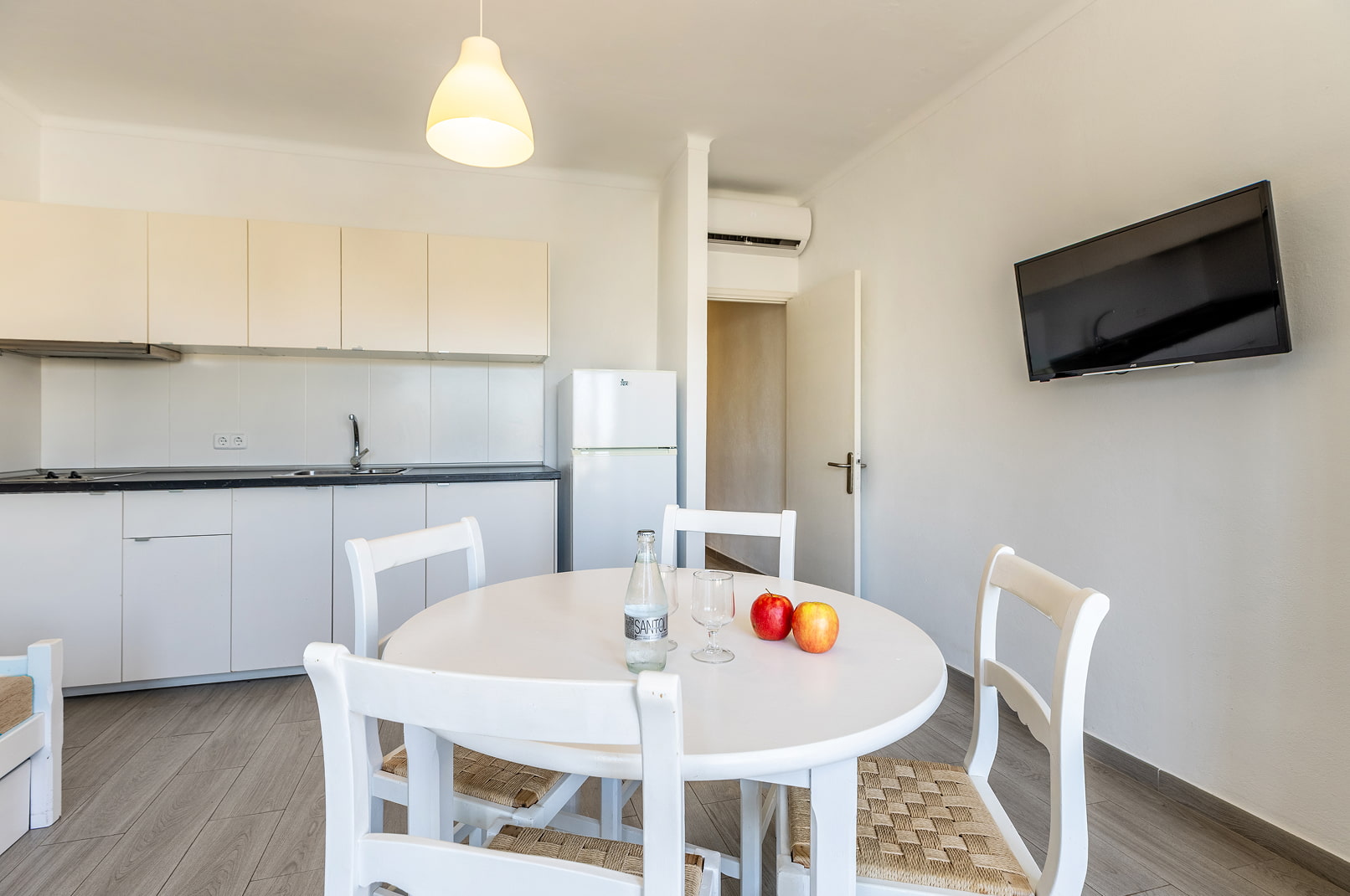 Cocina equipada y mesa, sillas y tv del apartamento basic